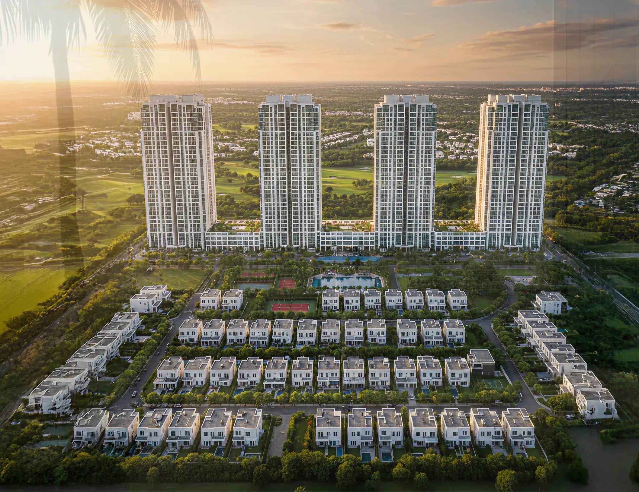 Aerial view of four residential towers surrounded by villas and green landscape