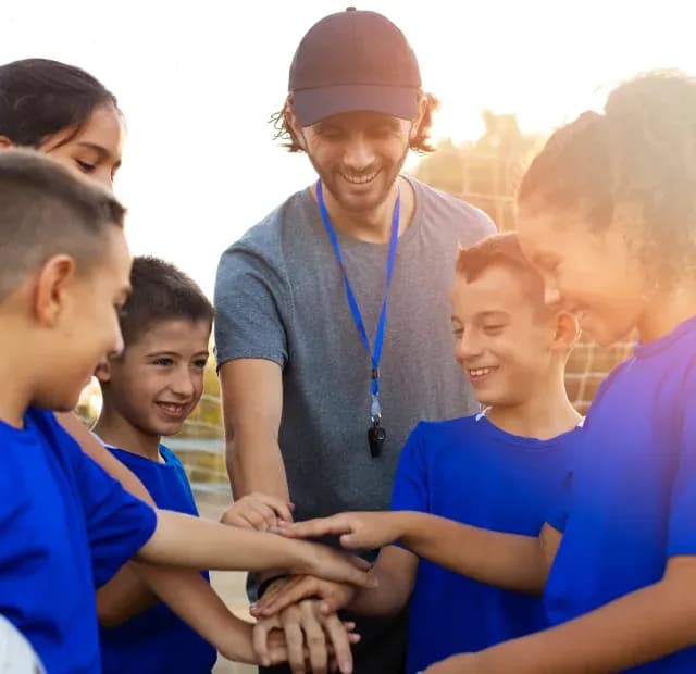 Volunteers stacking hands with children in a huddle