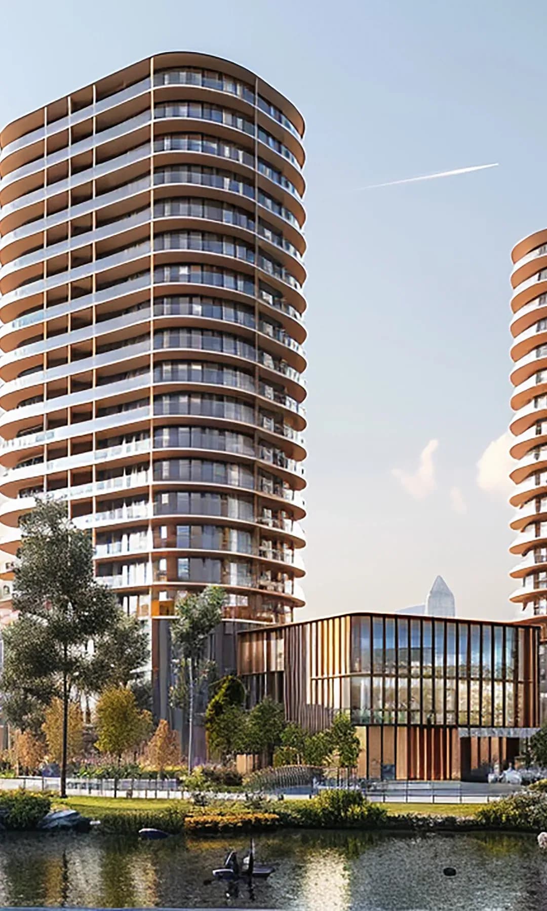 Two curved residential towers beside a landscaped lake